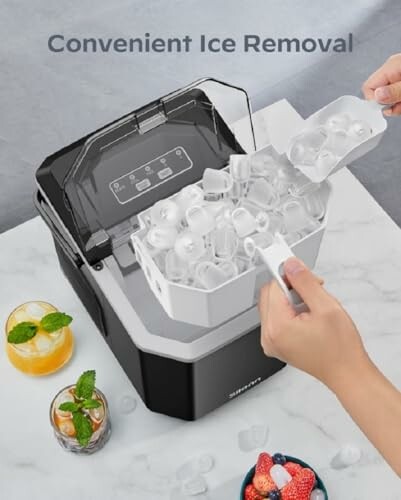 Person removing ice from an ice maker with drinks on a table.