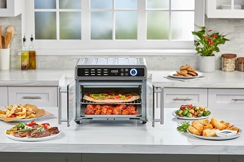 Air fryer with food on kitchen counter including pizza, chicken, fries, steak, and spring rolls.